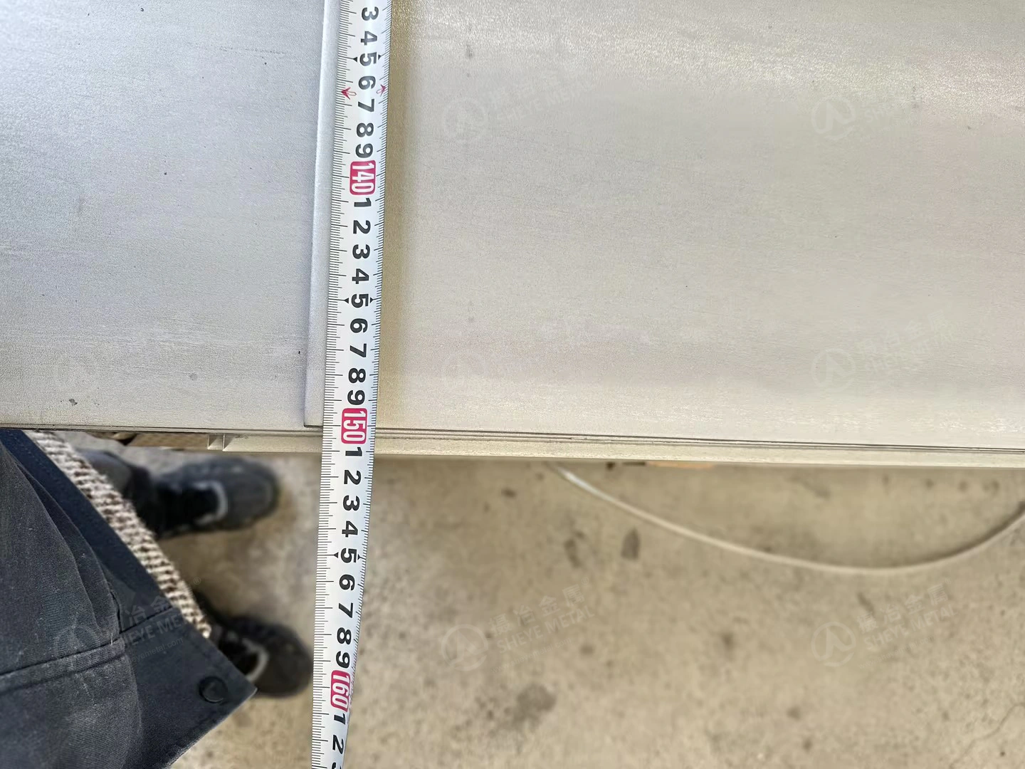 Close view of the measuring tape and edge during a width check on the nominal 1500 mm wide 310S plate.